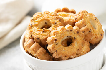 Shortbread in a white ceramic plate on a light table. A plate of cookies on the gray kitchen table. Cookies close up