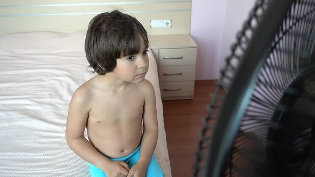 4K Coronavirus home video - Bare-chested boy feels cold sitting in front of ventilator
