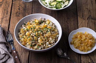 Traditional Middle Eastern dish, Mujadara of lentils, rice and fried onions with a salad of cabbage and cucumbers on wooden table, top view, selective focus