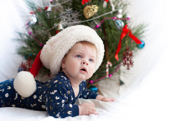 Obraz na płótnie Canvas infant in santa hat near christmas tree new year