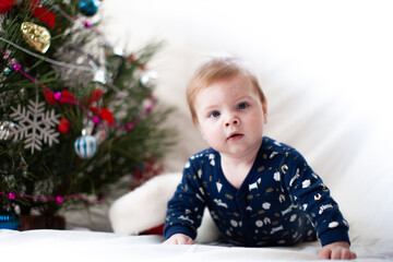 infant in santa hat near christmas tree new year