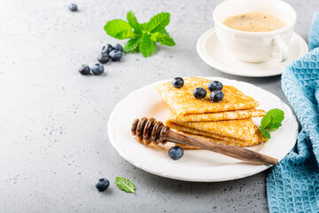 Delicious Tasty Homemade crepes or pancakes with blueberries, honey and mint on white plate. Healthy breakfast concept, gluten free. Copy space.