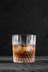Glass with whiskey or rom with ice cubes on concrete background.. Copy space. 