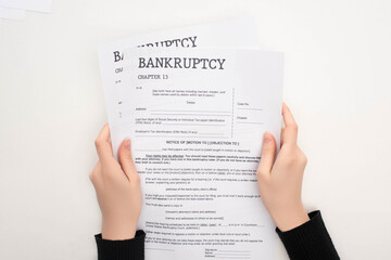 Fototapeta na wymiar partial view of woman holding bankruptcy papers on white background