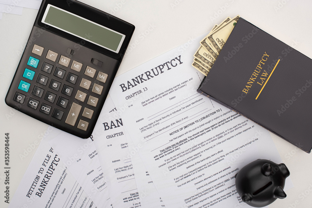 Wall mural top view of bankruptcy papers, law book with money, calculator and piggy bank on white background