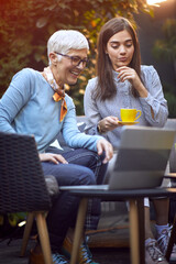 Senior woman and adult girl sitting outdoors at home and enjoying at coffee.