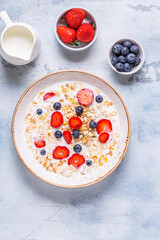 Healthy breakfast, bowl with oat granola, milk and berries.