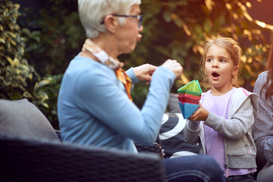 Happy  Grandparents Enjoying With Grandchild And Playing With Paper Boat.