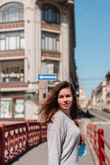 The girl went outside after the quarantine, walking around the city on the red bridge in St. Petersburg