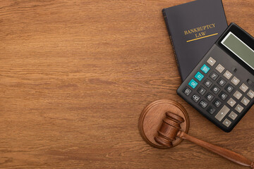 top view of gavel, bankruptcy law book and calculator on wooden background
