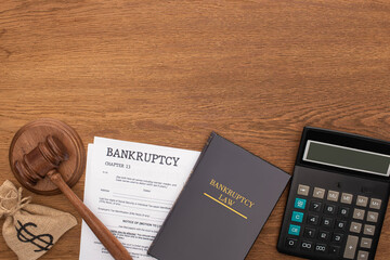 top view of calculator, bankruptcy law book, documents, money bag and gavel on wooden background
