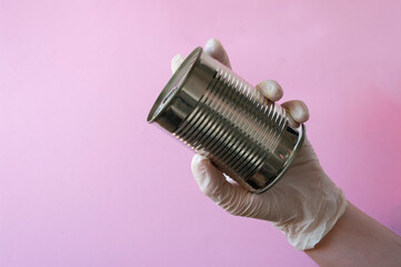Fototapeta na wymiar Hand in rubber glove holding canned food. Grocery.