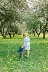 Mom with a child plays in the garden. Mom and son walk in the park. Relations between mom and son.