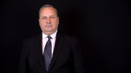 Old businessman in a suit. Isolated black background.