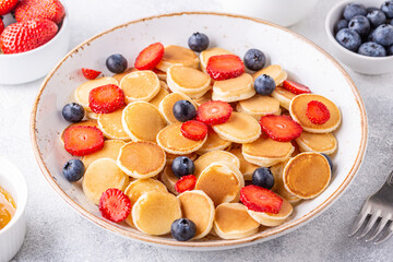 Tiny pancakes with strawberries and blueberries for breakfast.