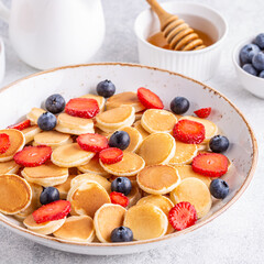 Tiny pancakes with strawberries and blueberries for breakfast.