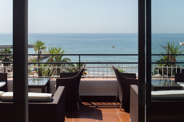 Chairs and tables on terrace with seascape and palm trees on coast in Catalonia, Spain