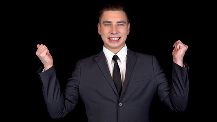 Young businessman snaps fingers on two hands. Man in a black suit on a black background