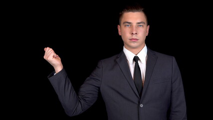 Young businessman clicks his fingers. Man in a black suit on a black background