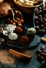 Handmade candies, two truffles with cocoa powder and two with coconut flakes. Chocolate candies inside of candy wrapper on blackstone stand