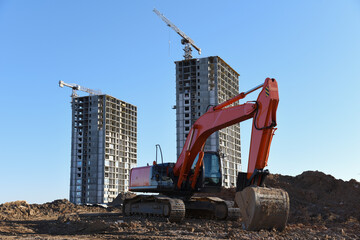 Excavator working at construction site on earthworks. Backhoe on road work digs ground. Paving out...