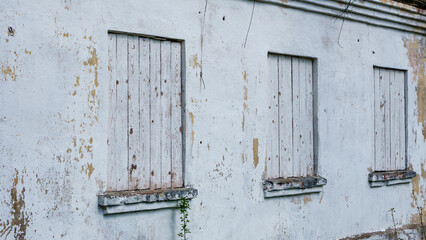 White wooden wall with closed windows with cracks and texture of old paint. Background for your design. Space for text.