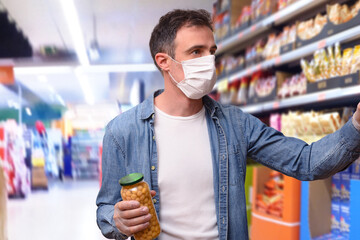 Protected man with food in hand choosing products in supermarket