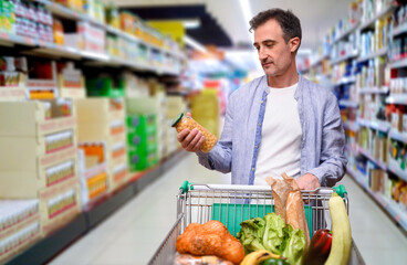 Supermarket customer choosing products in a supermarket aisle with cart