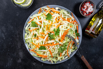 White cabbage salad coleslaw with carrot on grey kitchen table background. Top view, copy space