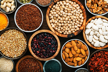 Superfoods, legumes, nuts, seeds and cereals set in bowls on wooden background. Superfood as chia, spirulina, beans, goji berries, quinoa, turmeric, mung bean, buckwheat, lentils, flax seed, wild rice