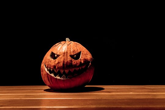 Lonely halloween pumpkin smile with black dark fire eyes mouth. Big spooky helloween symbol has darkest mad face and smiling with sharp teeth and bad look. Black orange nightmare of October 31st