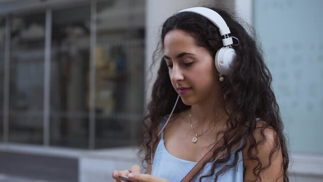 Happy young woman wearing headphones, listening to music and dancing