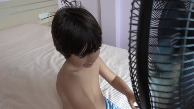 4K Coronavirus home video - Bare-chested child sits on bed in front of ventilator
