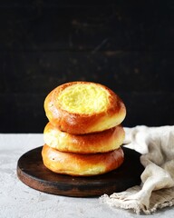 Homemade buns with cottage cheese (cheesecakes) in a dish on a gray background, Russian cuisine