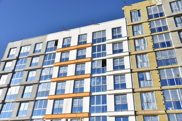 Construction of a new multi-storey building. Wall painting and insulation of the facade of the mineral wool.  Modern residential building. Housing renovation program