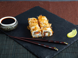 Set of sushi maki roll with sesame and soy sauce on a dark plate red background