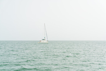 Fototapeta premium Small sailing boat in the rain in the middle of the sea