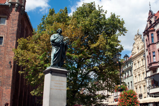 Torun Poland, statue of the  astronomer Nicolaus Copernicus, with streetscape of ratusz staromiejski in the background 