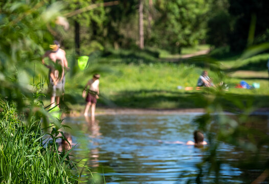 Children (out of focus) swimming in nature, in the River Chess at Chorleywood, Hertfordshire UK. Swimming oudoors in natural habitats is allowed during the coronavirus lockdown.