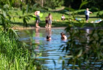 Children (out of focus) swimming in nature, in the River Chess at Chorleywood, Hertfordshire UK. Swimming oudoors in natural habitats is allowed during the coronavirus lockdown.