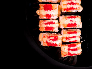 Set of sushi maki roll with red caviar on a dark plate.