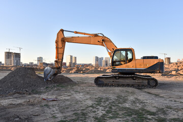 Excavator working at construction site on earthworks. Backhoe on road work digs ground. Paving out...