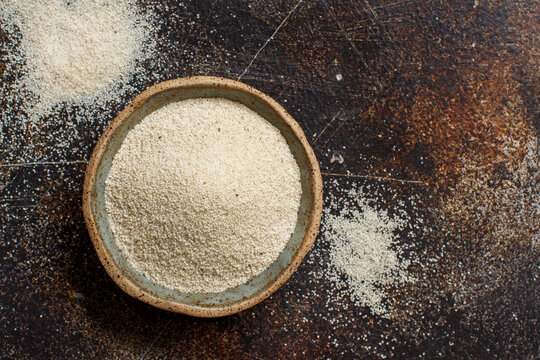 Raw uncooked fonio seeds in a bowl on a dark background