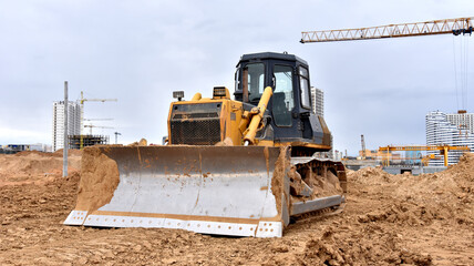 Dozer working at construction site. Bulldozer for land clearing, grading, pool excavation, utility trenching and foundation digging. Crawler tractor and earth-moving equipment