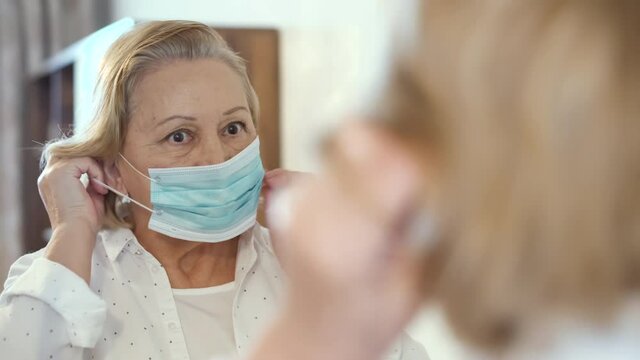 A woman puts on a face mask with a mirror to exit the street. Life during a pandemic and quarantine due to coronavirus covid-19
