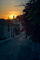 Picturesque picture of a sunset over a village with a stone path leading to the bougainvillea,