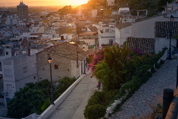 Fototapeta na wymiar Picturesque picture of a sunset over a village with a stone path leading to the bougainvillea