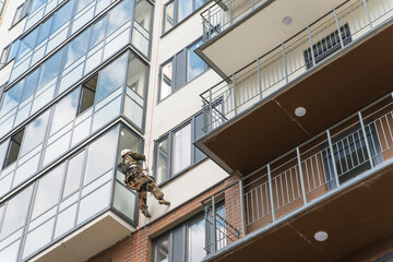 Fototapeta premium Outside of the multistory building washing of the facade of a industrial climber clean windows, bottom view. Worker alpinist