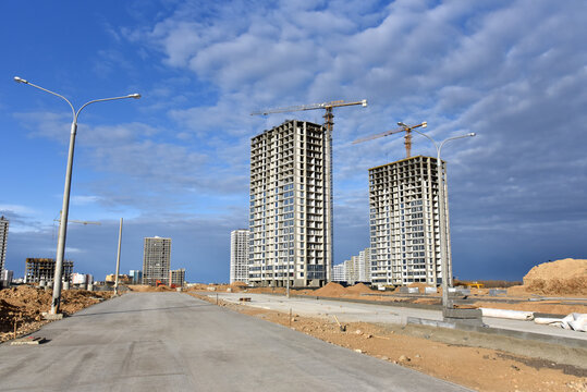 Concrete road construction. Ready Mix. Tower cranes in action at construction site on blue sky background