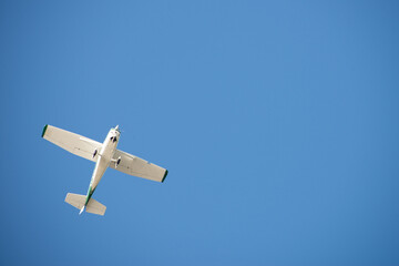 Vom Boden aus: kleines Motor-Flugzeug am wolkenlosen blauen Himmel